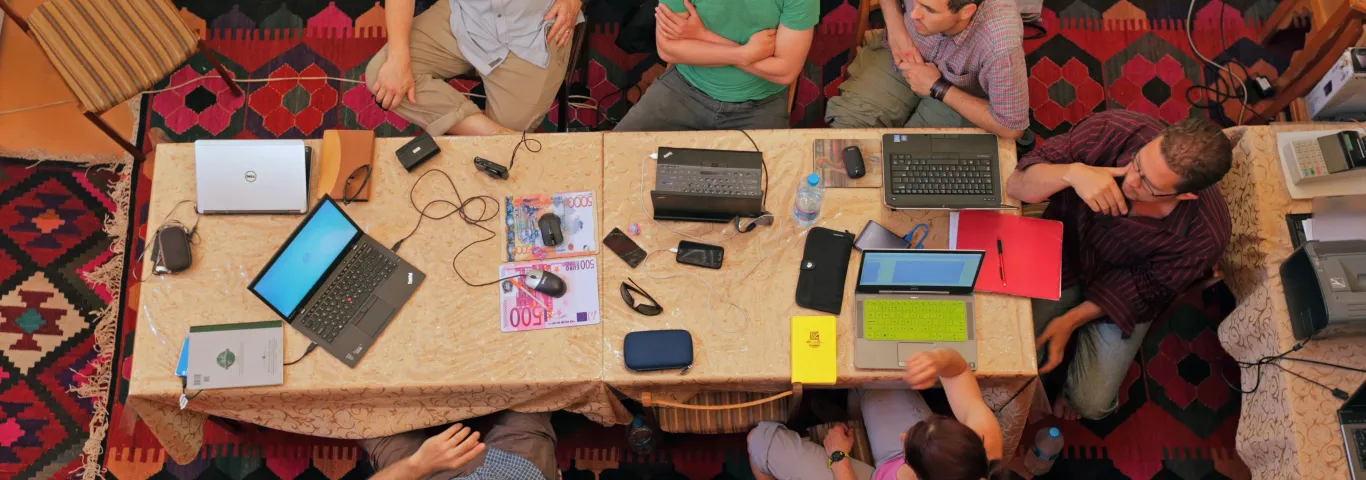 A team of six archeologists sitting around a table participating in a discussion.