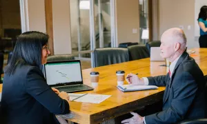 man and woman sit across a table form one another